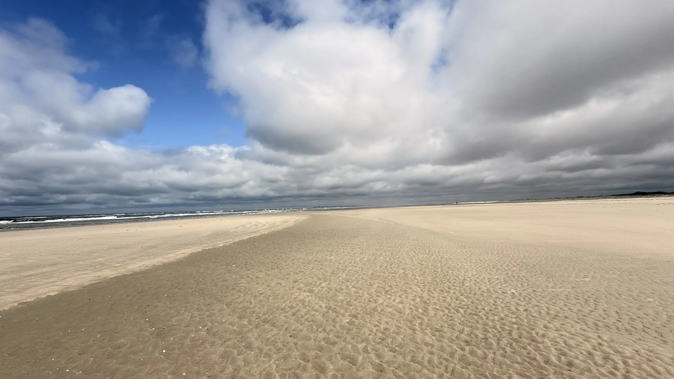 Leerer Sandstrand unter dramatischem Himmel