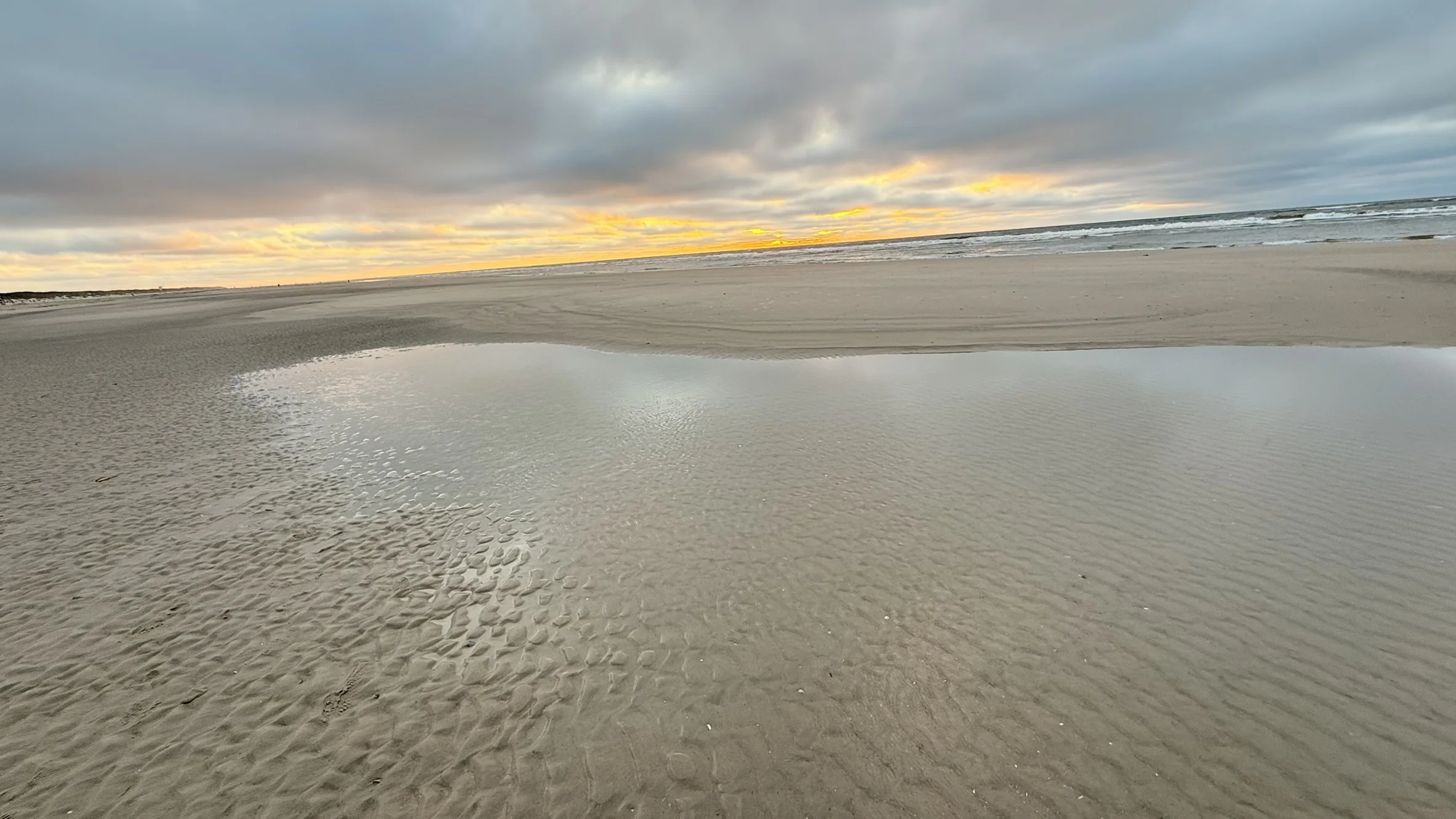 Abendhimmel spiegelt sich in einer Pfütze am Strand